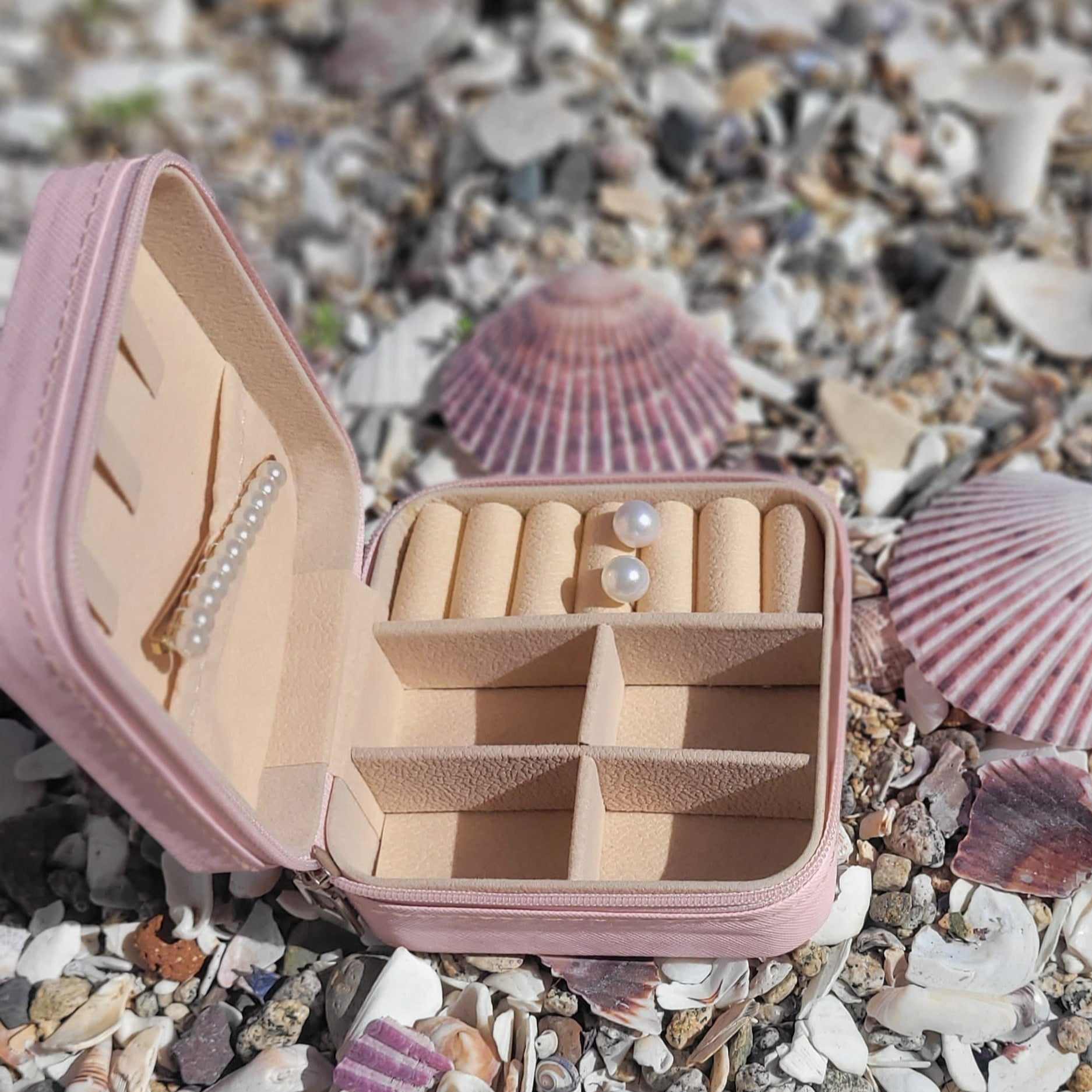 Joyero pequeño, de forma cuadrada, por fuera de color rosado, material de ecocuero. Al interior es color crema y cuenta con compartimientos para organizar joyas y accesorios. 