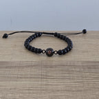 Pulsera de color negro, con cuentas redondas, y una gema al centro que contiene una foto personalizada. 
