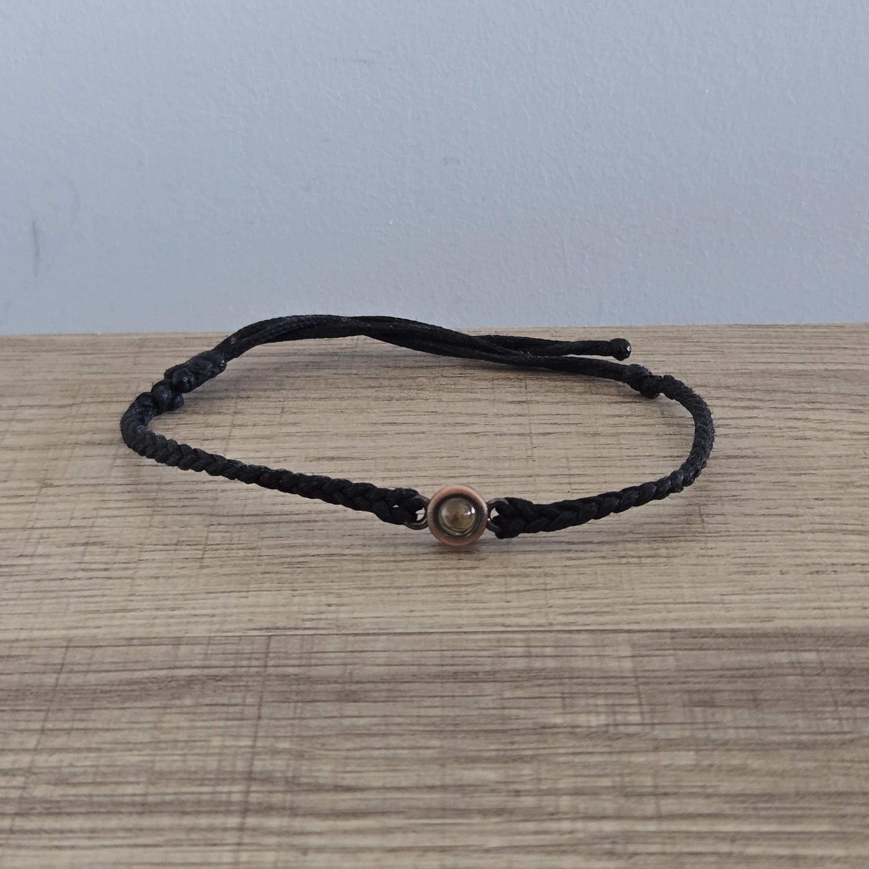 Pulsera unisex, de tela trenzada color negro y gema de acero inoxidable. Cuenta con una foto personalizada. 